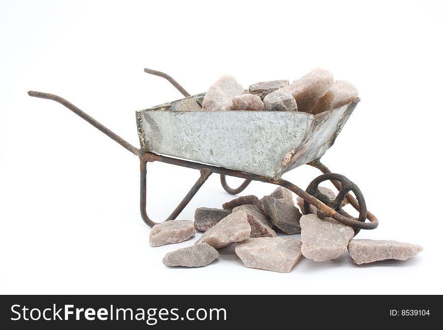 This is a wheelbarrow with rocks in it and around it. This is a wheelbarrow with rocks in it and around it