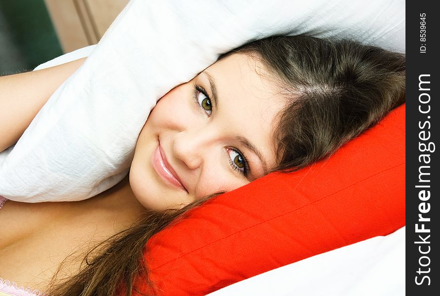 Beautiful young brunette woman sleeping in bed and covering her head with a pillow. Beautiful young brunette woman sleeping in bed and covering her head with a pillow