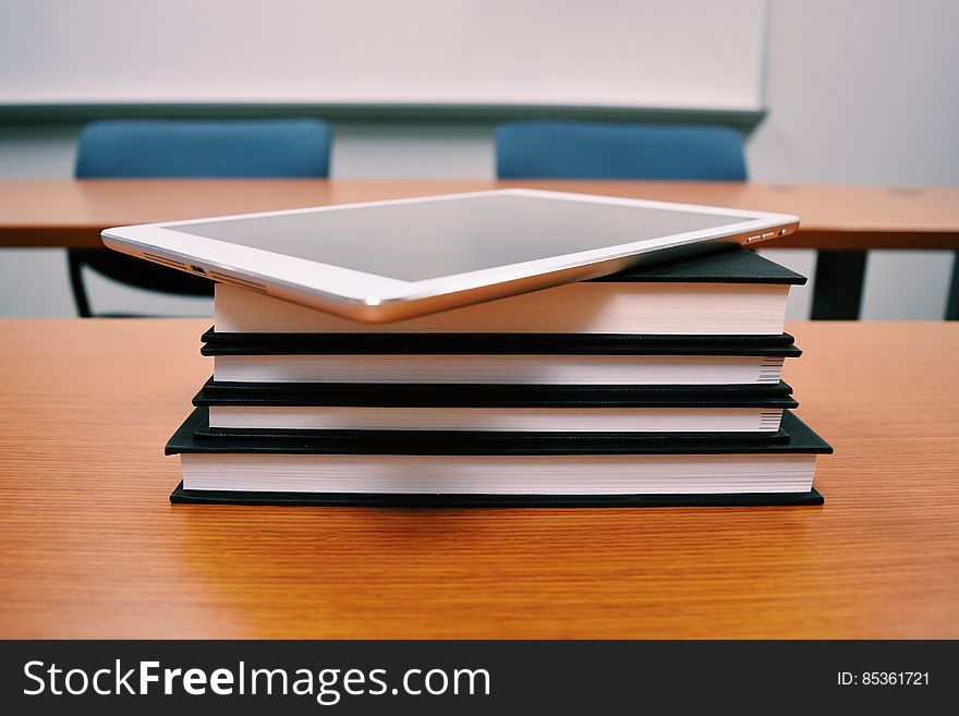 Tablet on stack of books on desk in school classroom. Tablet on stack of books on desk in school classroom.