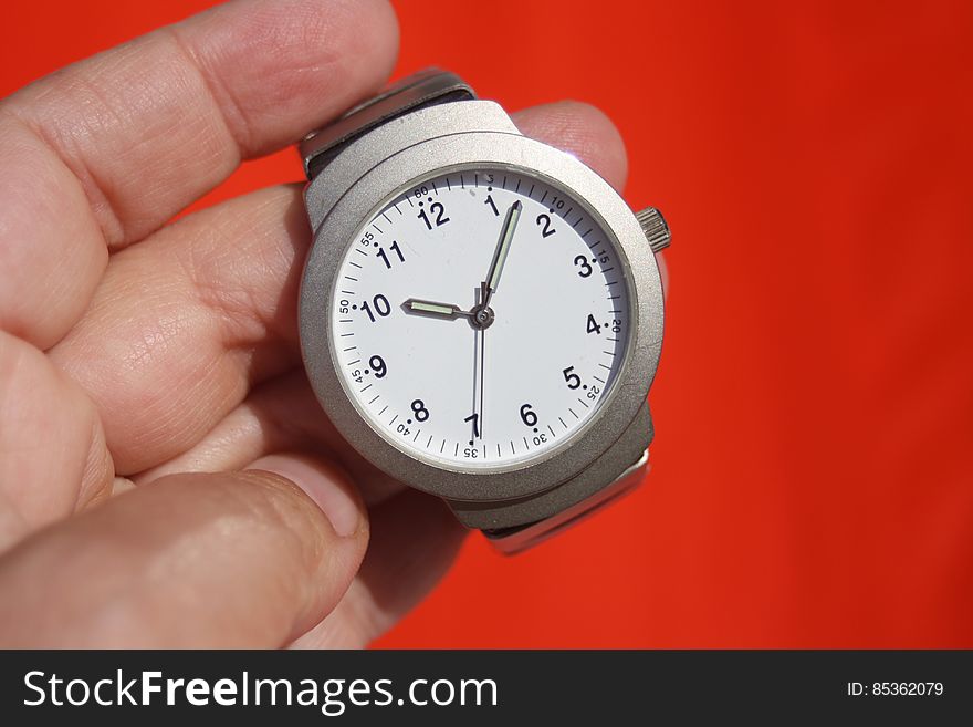 Person Holding Grey Round Analog Watch at 10:07