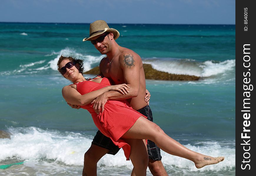 A young couple getting romantic at a mexican beach resort.with ocean waves rolling in. A young couple getting romantic at a mexican beach resort.with ocean waves rolling in.