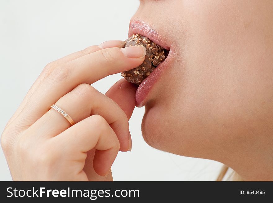 Girl eating chocolate candy isolated on white