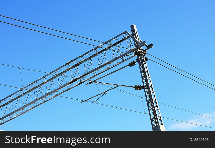 Railway pylons of the high tension line with blue sky