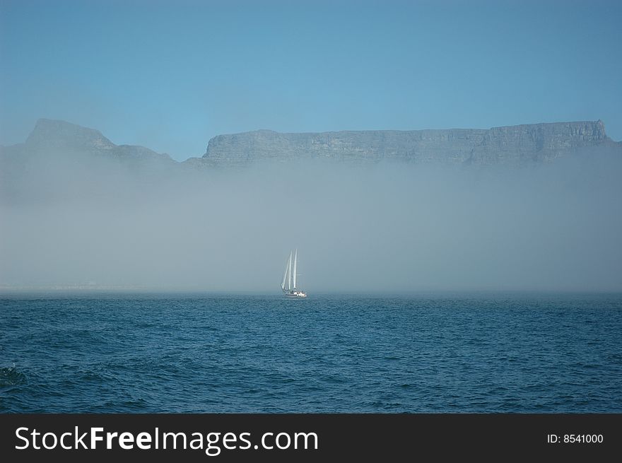 Sailboat in Cape Town sailing through fog on the open ocean. Sailboat in Cape Town sailing through fog on the open ocean