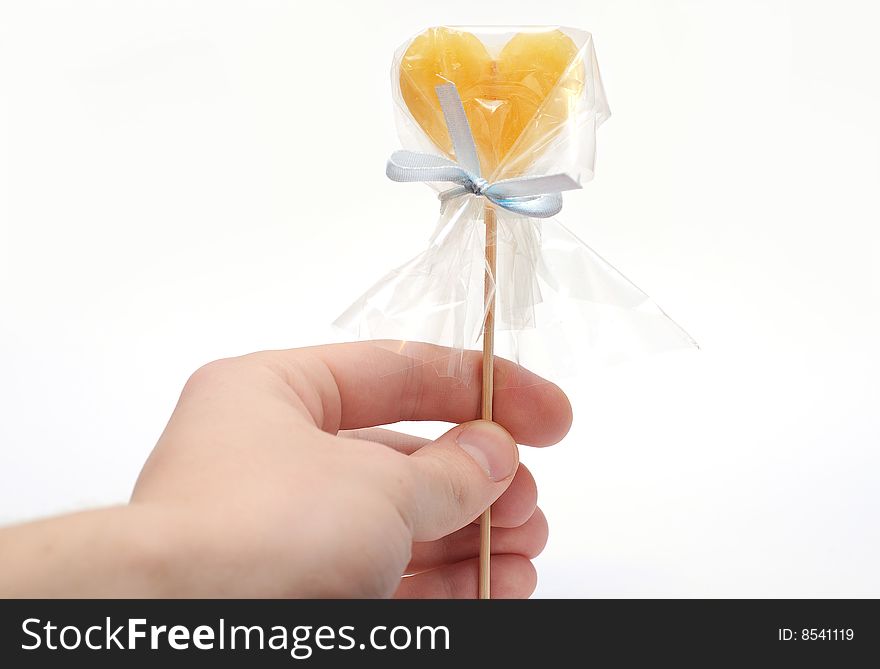 Hand with caramel candy on stick as a Valentine treat on white background isolated. Hand with caramel candy on stick as a Valentine treat on white background isolated