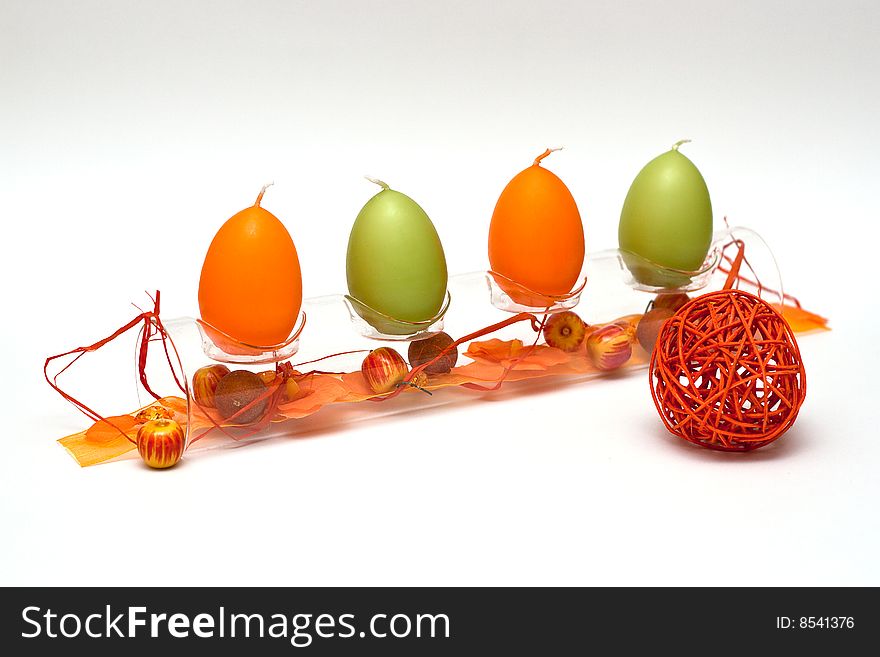 A composition of a glass tube with egg formed candles and a bit of spring feeling for easter and a red ball in front. A composition of a glass tube with egg formed candles and a bit of spring feeling for easter and a red ball in front