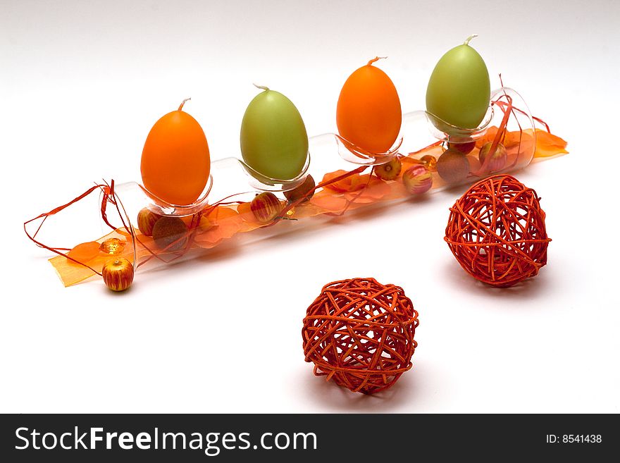 A composition of a glass tube with egg formed candles and a bit of spring feeling for easter and two red balls in front. A composition of a glass tube with egg formed candles and a bit of spring feeling for easter and two red balls in front