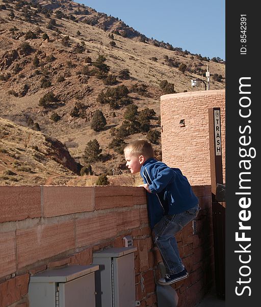 A color image of a young boy looking over the edge into the unknown.
