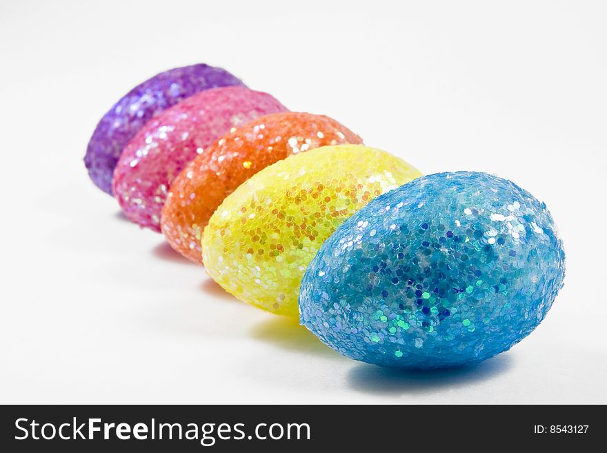 Five colorful eggs isolated in white arranged in a row shot from the side. Five colorful eggs isolated in white arranged in a row shot from the side