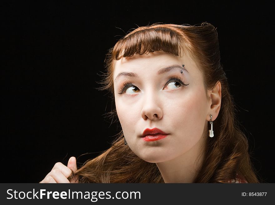 Pretty pensive retro-style woman touching her hair, looking up over dark background