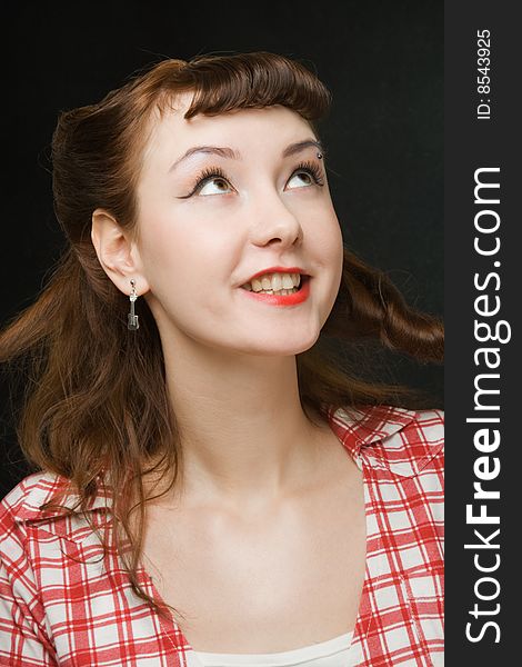 Pretty retro-style woman smiling and looking up over dark background. Pretty retro-style woman smiling and looking up over dark background