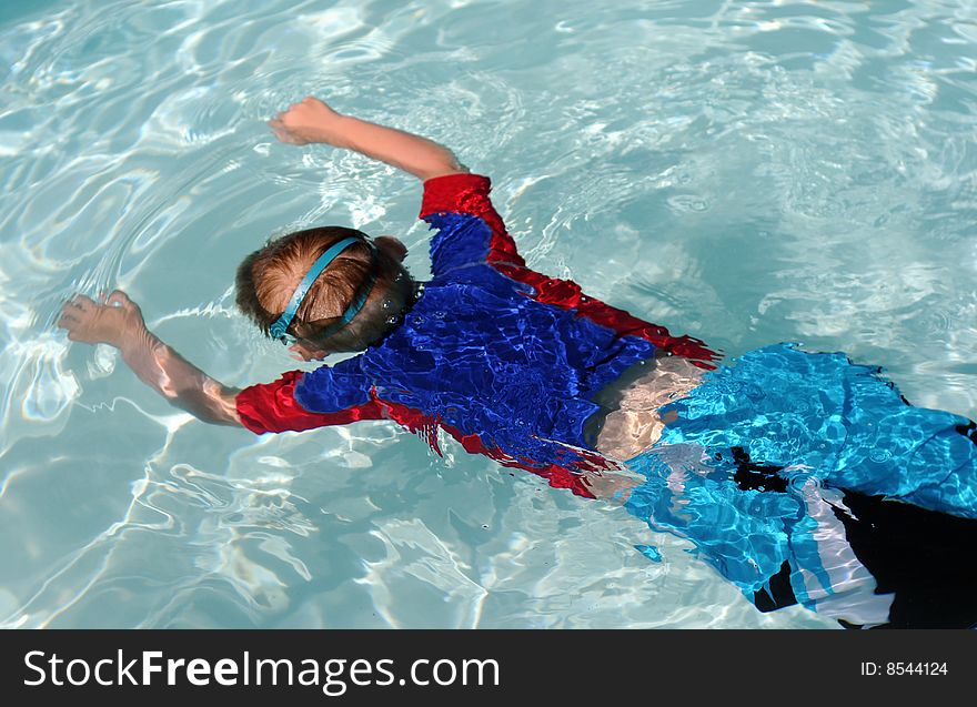 Boy floating in a pool with goggles. Boy floating in a pool with goggles