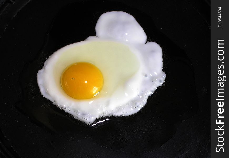 An egg is being cooked in a pan .