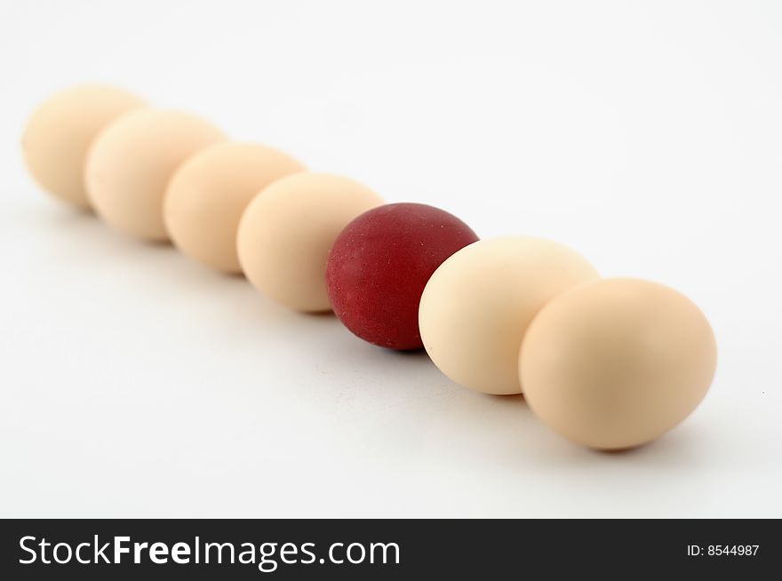 Row of easter eggs, one egg is red, against white background