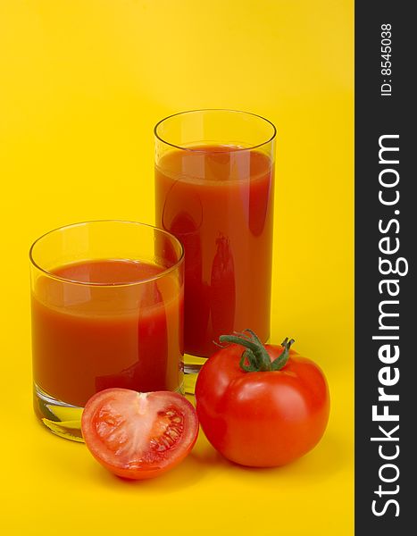 Ripe juicy tomatoes and glass of tomato juice on a yellow background. Ripe juicy tomatoes and glass of tomato juice on a yellow background