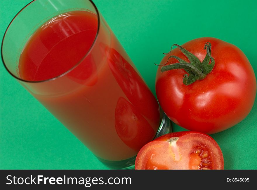 Tomatoes and fresh tomato juice on a green background. Tomatoes and fresh tomato juice on a green background