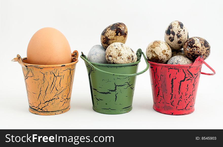 A row of toy buckets each with eggs on white background. A row of toy buckets each with eggs on white background