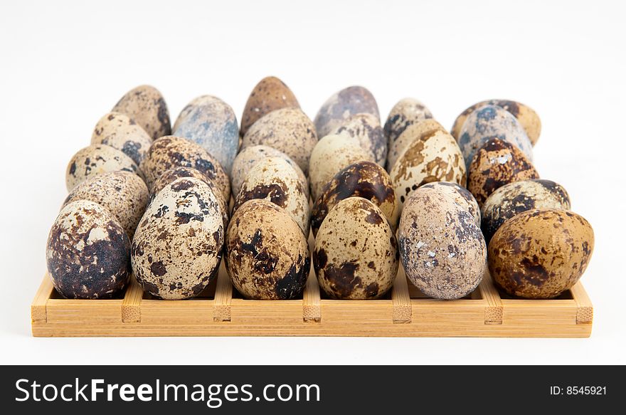 Quail eggs placed on a square wooden grid on white background. Quail eggs placed on a square wooden grid on white background