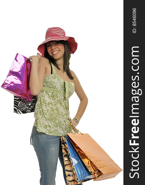 Cute young woman making shopping with lots of colorful shopping bags, blue jeans and funny pink hat. Isolated on white. Cute young woman making shopping with lots of colorful shopping bags, blue jeans and funny pink hat. Isolated on white