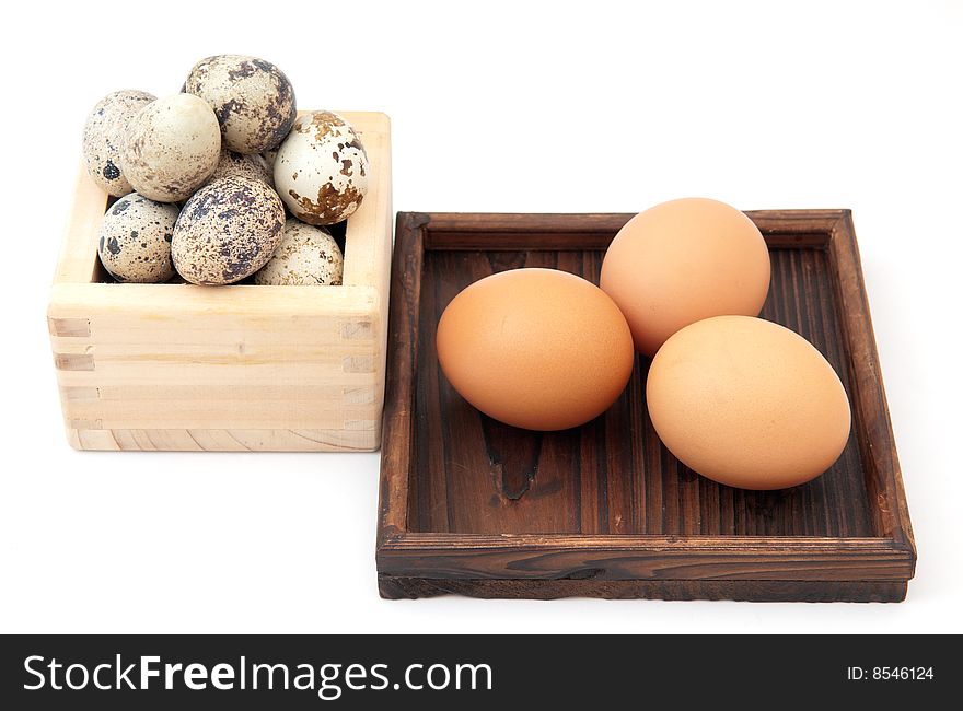 Zen inspired arrangement of quail and chicken eggs in wooden containers on white background. Zen inspired arrangement of quail and chicken eggs in wooden containers on white background