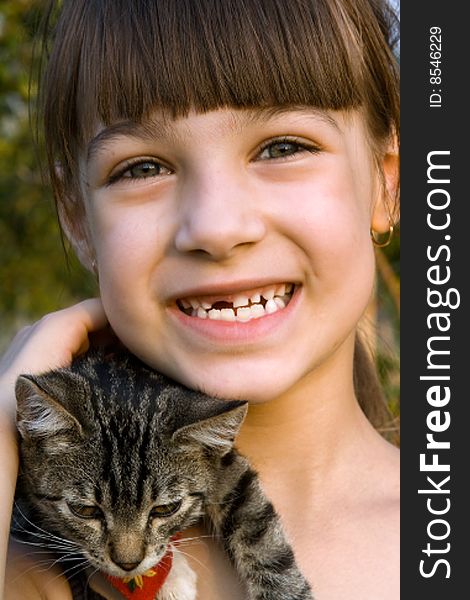 Little girl is smiling and holding small cat. Little girl is smiling and holding small cat