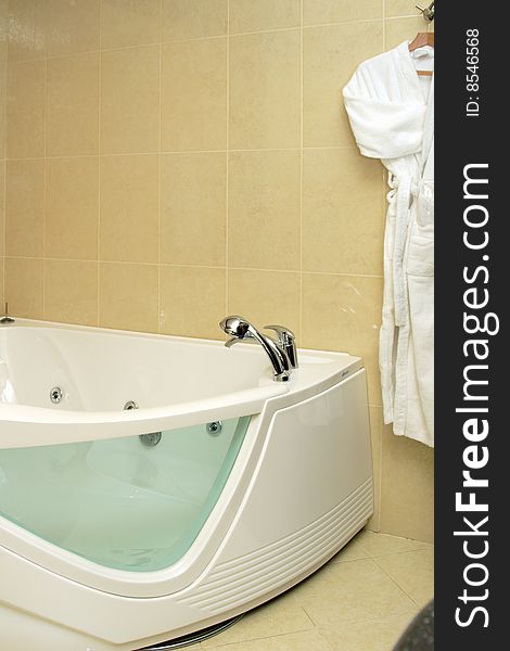 Fragment of luxury bathroom in a hotel suite, with bathtub and bathrobe. Fragment of luxury bathroom in a hotel suite, with bathtub and bathrobe