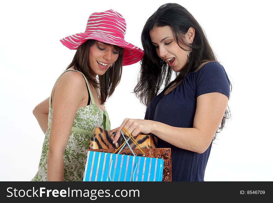 Young cute woman making shopping with her friend, both in casual wear holding shopping bags. One shows to other what she've bought. Isolated on white background. Young cute woman making shopping with her friend, both in casual wear holding shopping bags. One shows to other what she've bought. Isolated on white background