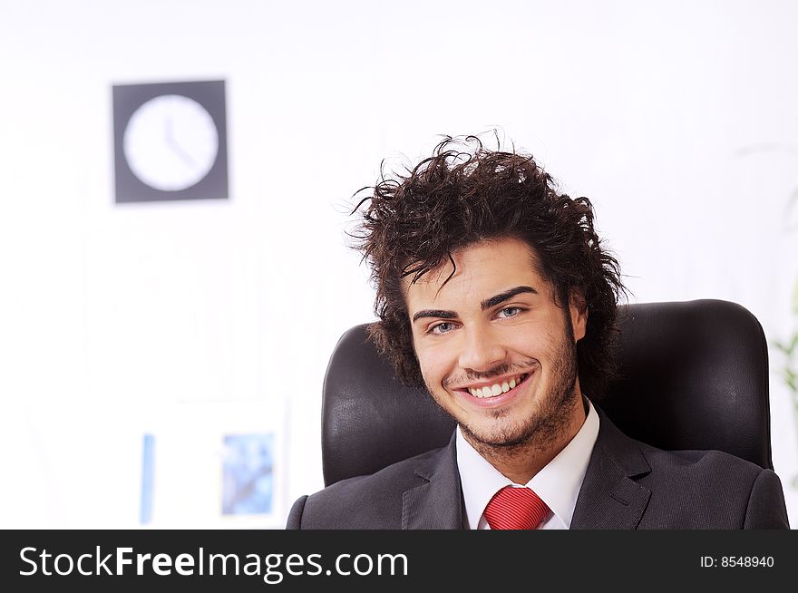 Businessman in the office, smiling and looking in camera. Businessman in the office, smiling and looking in camera
