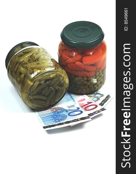 Some euro banknotes under some jars of vegetables. Some euro banknotes under some jars of vegetables