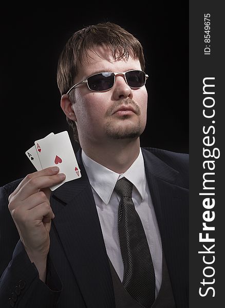 Man in suit with sun glasses playing poker on green table. Chips and cards on the table. Man in suit with sun glasses playing poker on green table. Chips and cards on the table.