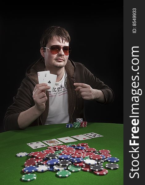 Man with sun glasses playing poker on green table. Chips and cards on the table. Man with sun glasses playing poker on green table. Chips and cards on the table.