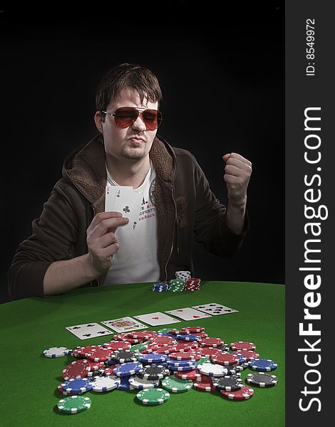 Man with sun glasses playing poker on green table. Chips and cards on the table. Man with sun glasses playing poker on green table. Chips and cards on the table.