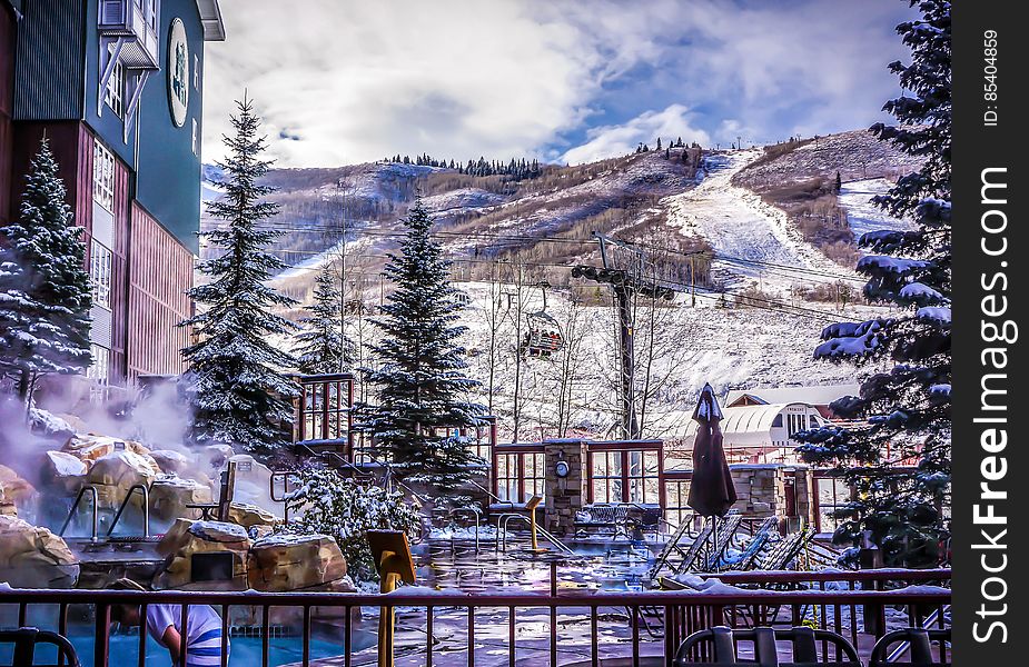 Exterior of resort with hot tub in snowy mountain landscape on sunny day. Exterior of resort with hot tub in snowy mountain landscape on sunny day.