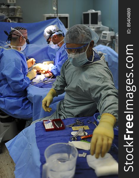 Surgeons around table in operating room during medical procedure. Surgeons around table in operating room during medical procedure.