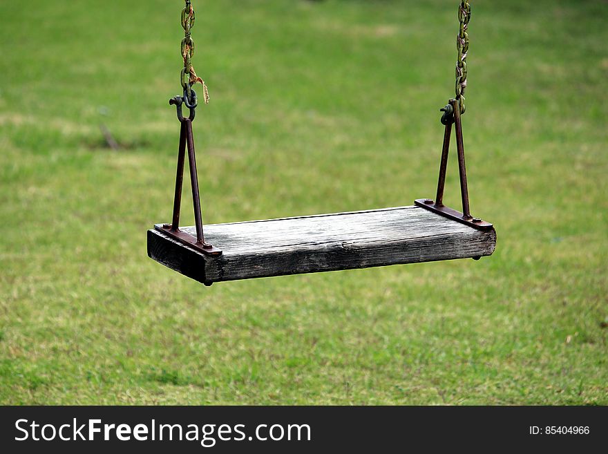 A wooden swing on the grass.