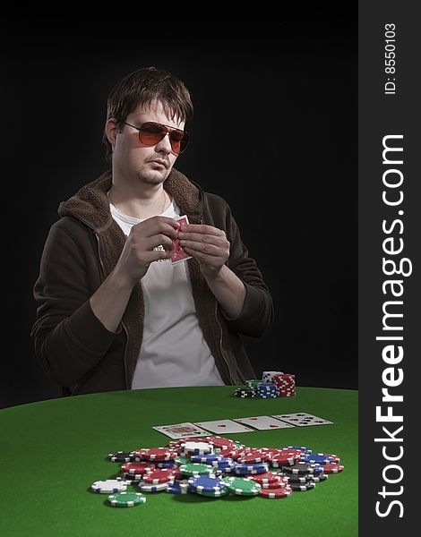 Man with sun glasses playing poker on green table. Chips and cards on the table. Man with sun glasses playing poker on green table. Chips and cards on the table.