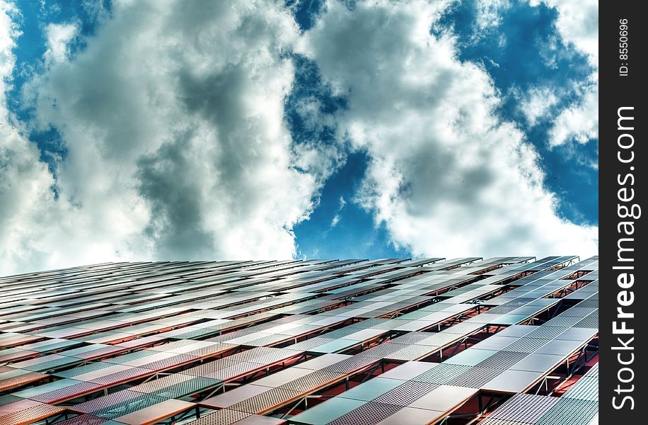 Building with interesting panel structure against a bright blue sky with interesting clouds formation. Building with interesting panel structure against a bright blue sky with interesting clouds formation