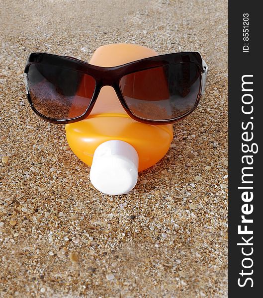 Antisun cream and antisun glasses on marine sand