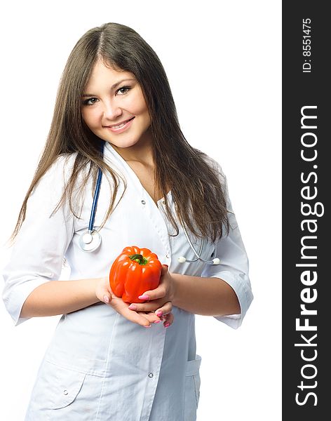 Beautiful young doctor wearing white uniform holding a red pepper in her hands. Beautiful young doctor wearing white uniform holding a red pepper in her hands