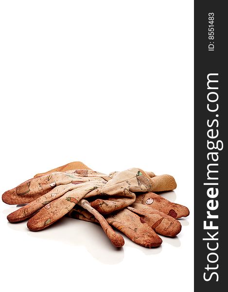 Vertical view of old worn work gloves on reflective white surface