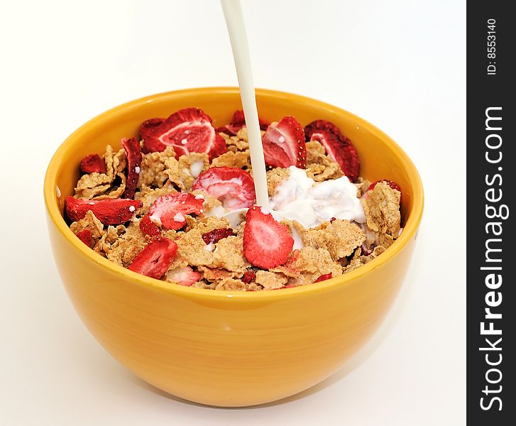 Milk being poured on a bowl of corn flakes with strawberry flakes. Milk being poured on a bowl of corn flakes with strawberry flakes