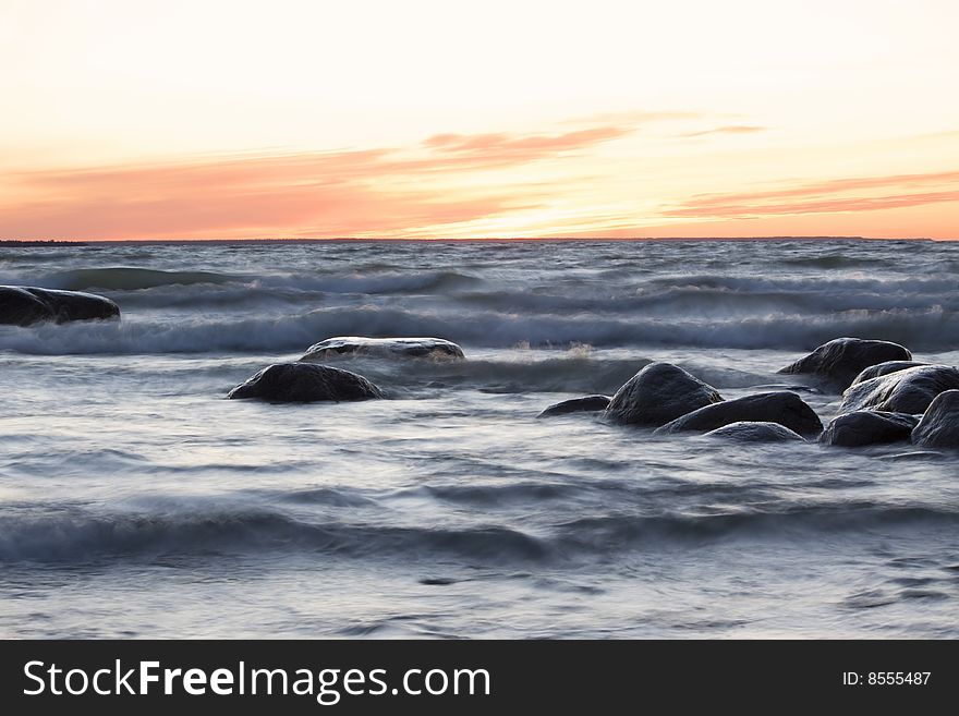 Sea at sunset, stones and soft waves