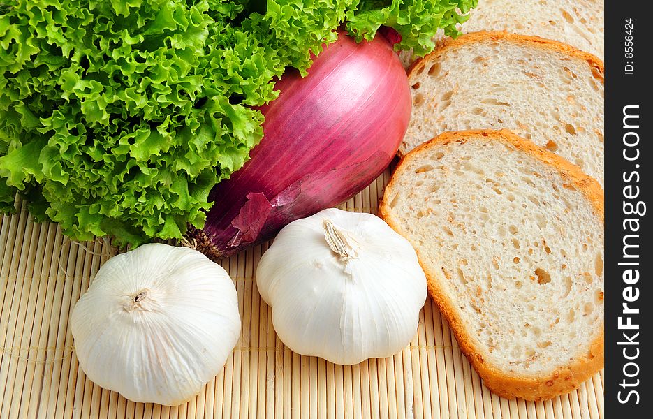 Salad, garlic, onion and bread on wooden background. Salad, garlic, onion and bread on wooden background
