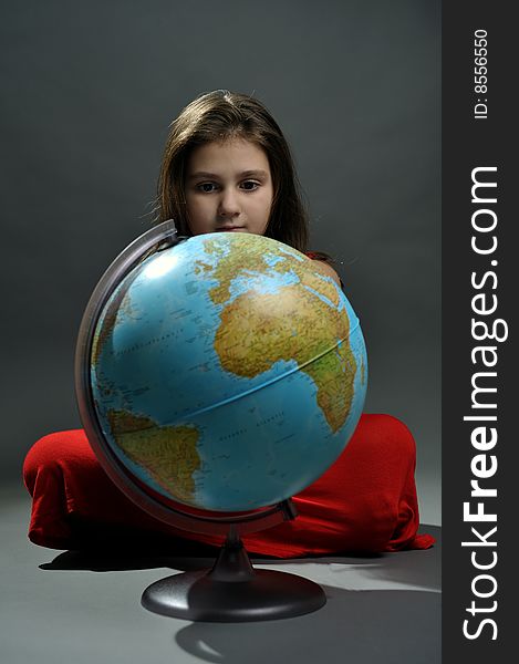 Girl in red dress standing behind a globe. Girl in red dress standing behind a globe
