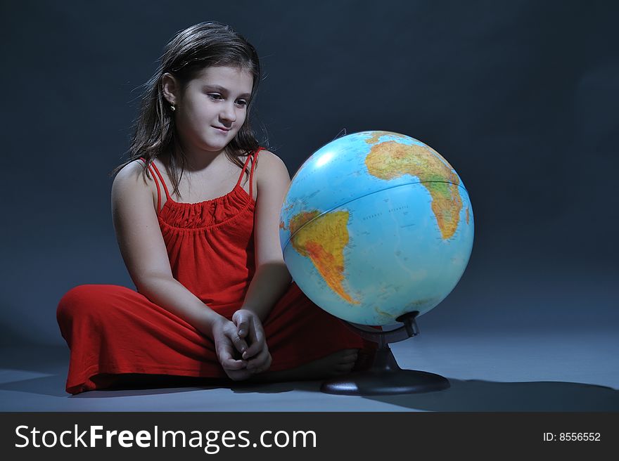 Girl in red dress standing behind a globe. Girl in red dress standing behind a globe
