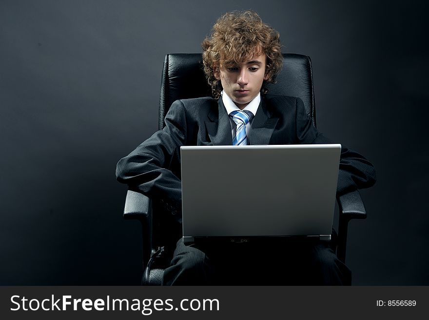 Young businessman standing on office chair and using laptop. Young businessman standing on office chair and using laptop