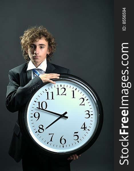 Young businessman holding a big clock in hands. Young businessman holding a big clock in hands