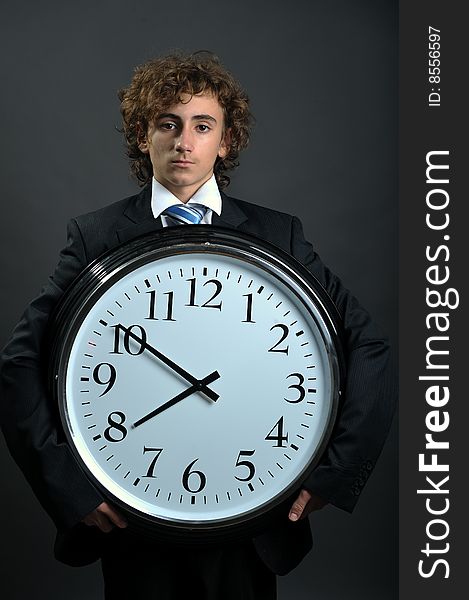 Young businessman holding a big clock in hands, deadline concept. Young businessman holding a big clock in hands, deadline concept