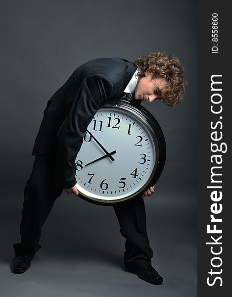 Young businessman holding a big clock in hands. Young businessman holding a big clock in hands