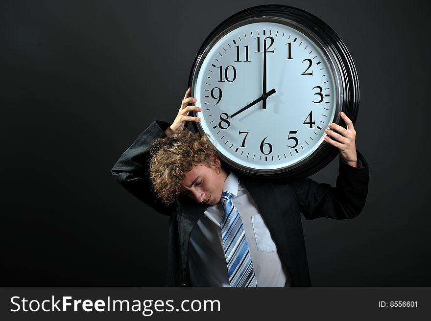 Young businessman holding a big clock on shoulder. Young businessman holding a big clock on shoulder